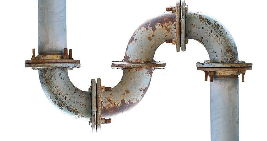 Tubería de metal bajo el piso de una fábrica deteriorada por la corrosión local