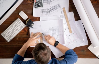 Arquitecto dibujando planos arquitectónicos sobre un escritorio
