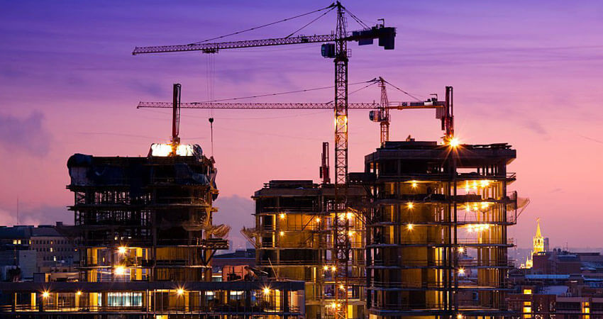 Estructura de un edificio con grúas en el techo durante su proceso de construcción al atardecer