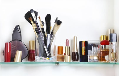 Repisa flotante moderna de vidrio con brochas, labiales, barnices y perfumes