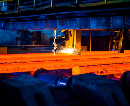 Industria metalúrgica produciendo perfiles de acero al rojo vivo para su corte