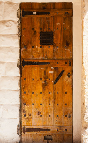 Puerta de herrería rústica elaborada en madera con elementos y remaches en hierro forjado