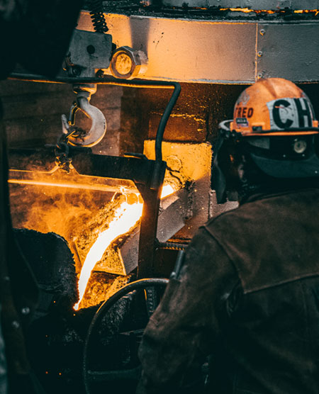 Trabajador de la industria metalúrgica vertiendo metal fundido de un horno