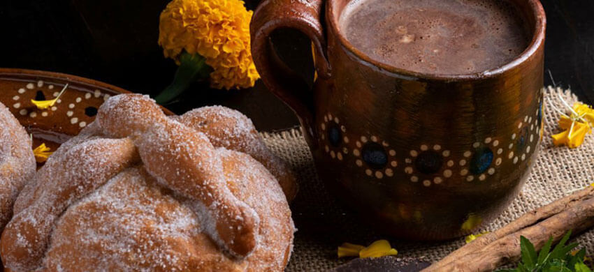 Acercamiento a una ofrenda con pan de muerto y chocolate