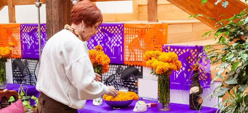 Mujer colocando ofrenda de día de muertos en su casa